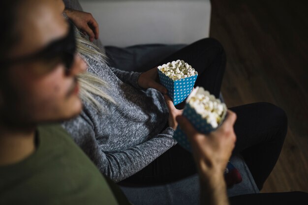 Pareja sin rostro con película de observación de palomitas de maíz