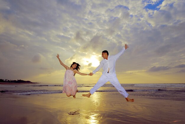 Pareja saltando en la playa