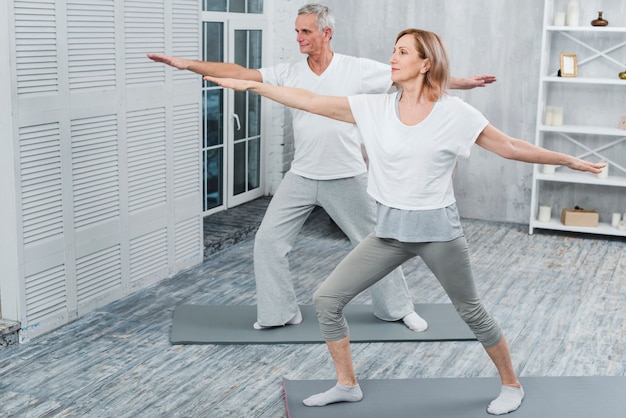 Pareja sana realizando ejercicio en estera de yoga en casa