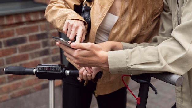 Pareja con scooters eléctricos y smartphone al aire libre