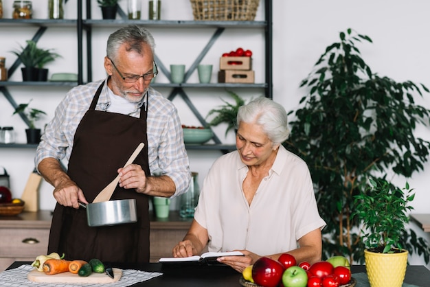 Pareja Senior mirando receta en la cocina