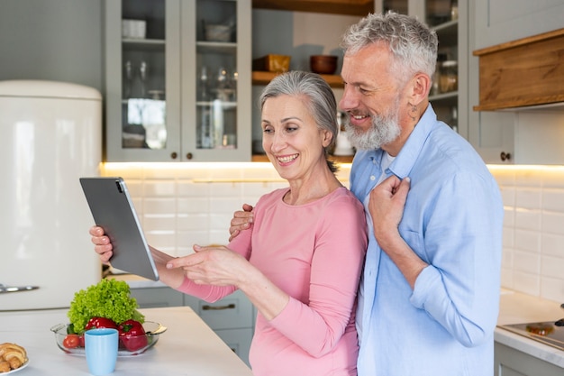 Pareja senior sonriente con tableta de tiro medio