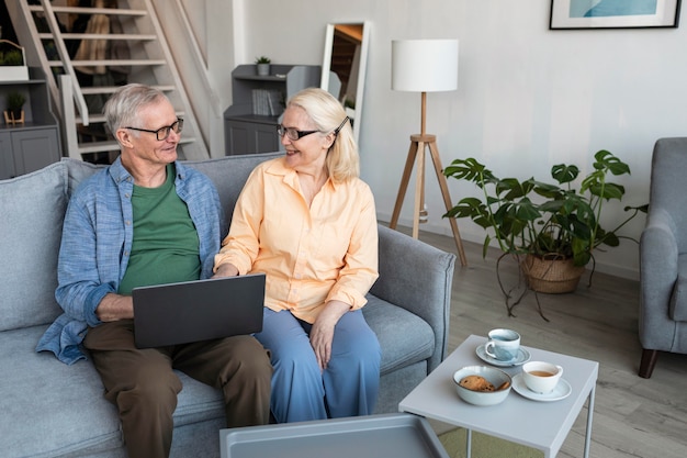 Pareja senior sonriente de tiro medio con portátil