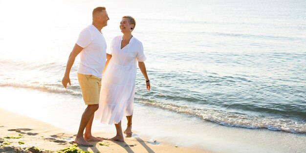 Pareja senior de tiro completo divirtiéndose en la playa