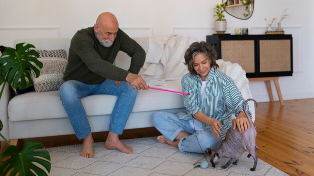 Pareja senior de tiro completo con gato en casa