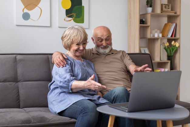 Pareja senior de tiro medio mirando portátil