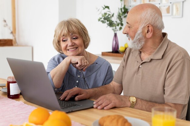 Pareja senior de tiro medio con portátil