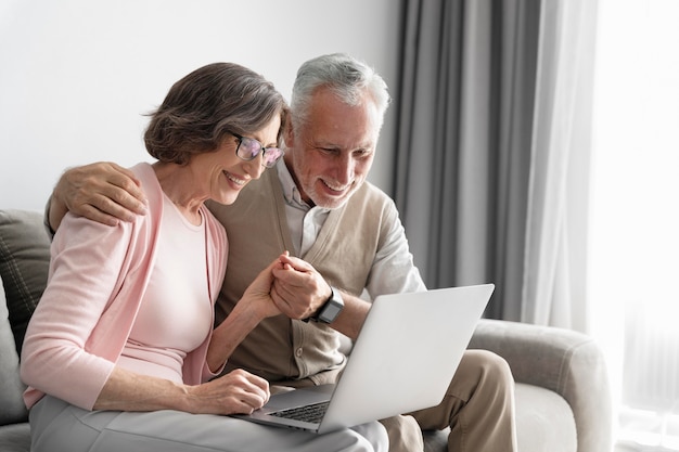 Pareja senior de tiro medio con portátil