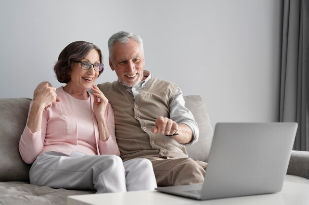 Pareja senior de tiro medio con portátil