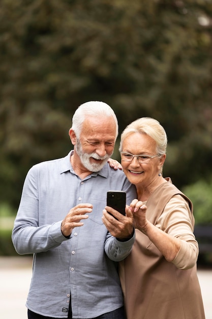 Pareja senior de tiro medio con smartphone