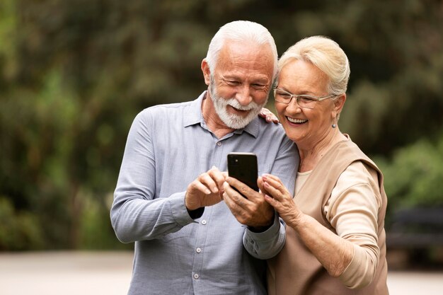 Pareja senior de tiro medio con teléfono