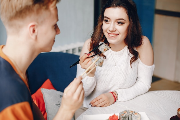 Pareja sentada en un café y comiendo sushi