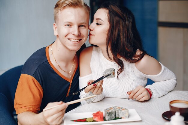 Pareja sentada en un café y comiendo sushi