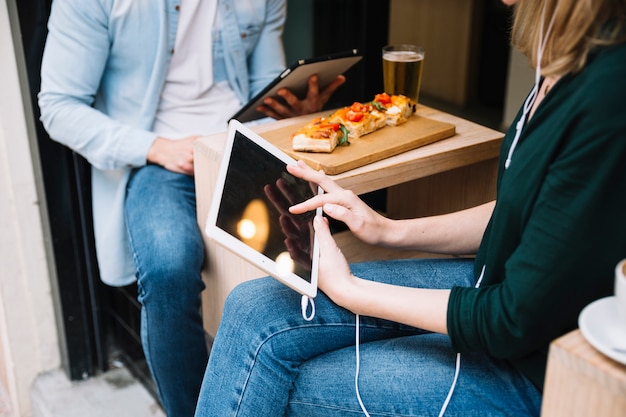 Pareja sentada en la cafetería y usando tabletas