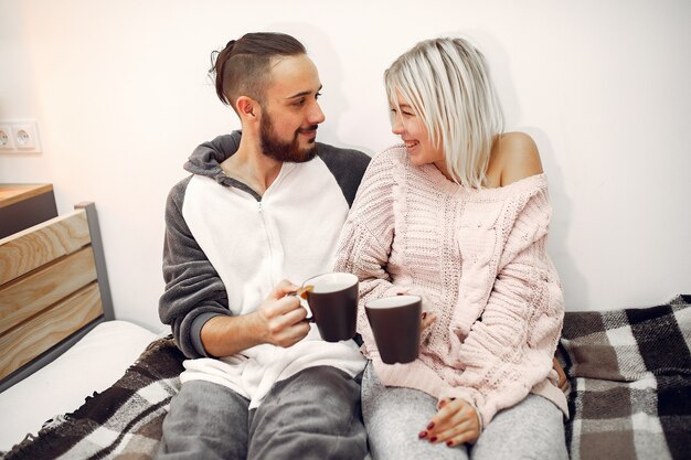 Pareja sentada en una cama en una habitación tomando café