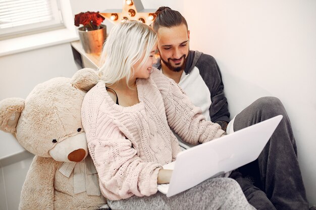 Foto gratuita pareja sentada en una cama en una habitación y usa una computadora portátil