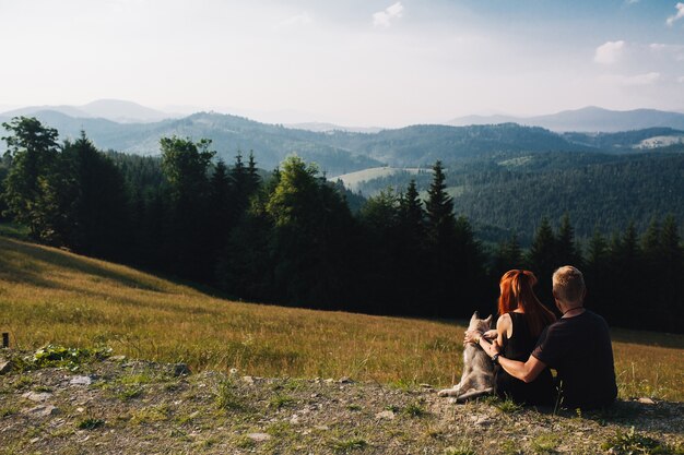 Pareja sentada en un campo verde mirando la naturaleza