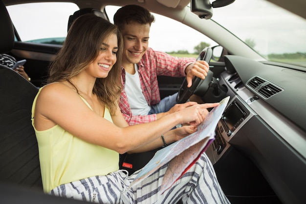 Foto gratuita pareja sentada en el coche que señala en el mapa