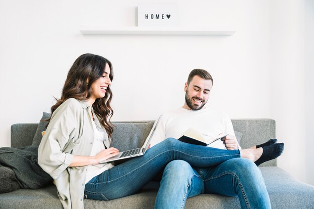 Pareja sentada con la computadora portátil y el libro