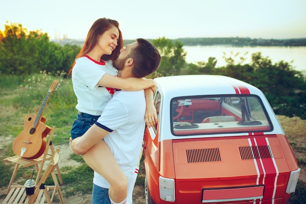 Pareja sentada y descansando en la playa en un día de verano cerca del río. Amor, familia feliz, vacaciones, viajes, concepto de verano.