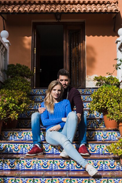 Pareja sentada en hermosas escaleras fuera