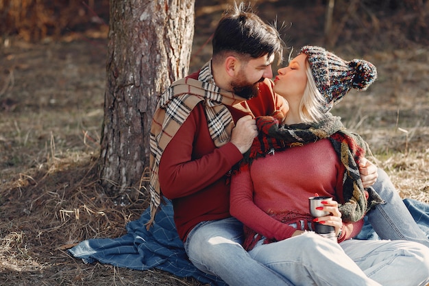 Pareja sentada junto a un árbol en un bosque de primavera