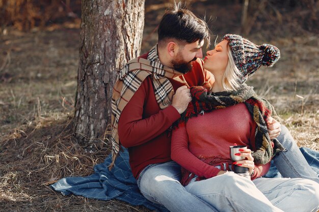 Pareja sentada junto a un árbol en un bosque de primavera