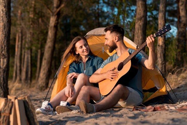 Pareja sentada junto a la carpa y cantando.