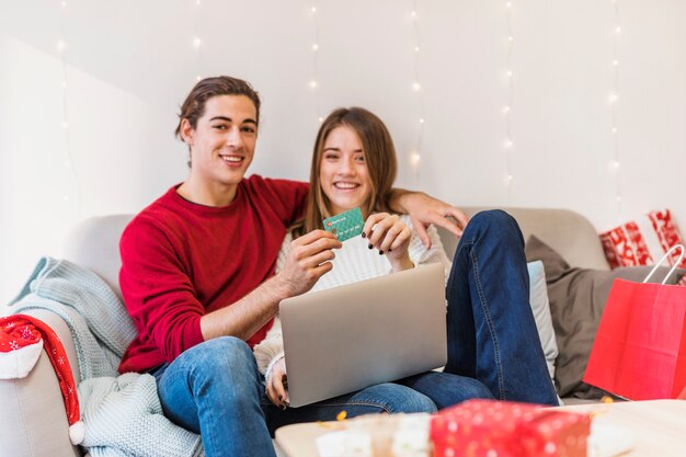 Pareja sentada con laptop y tarjeta de crédito