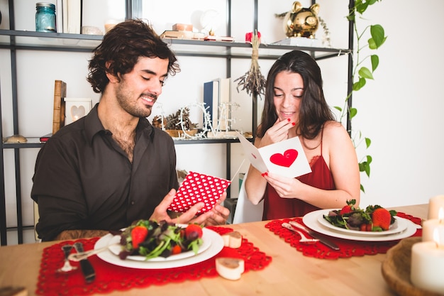 Foto gratuita pareja sentada en una mesa para comer leyendo postales románticas