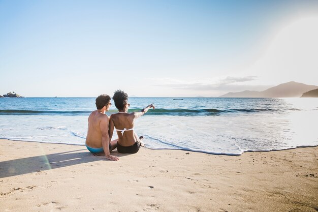 Pareja sentada por la orilla en la playa