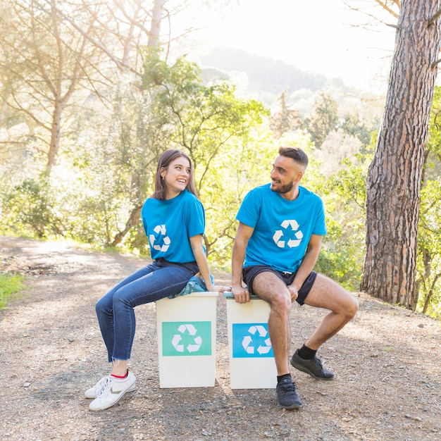 Pareja sentada en papeleras en el bosque