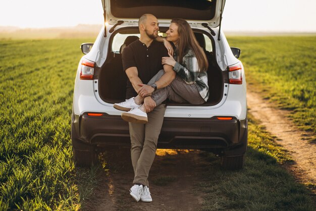 Pareja sentada en la parte trasera del automóvil en el campo