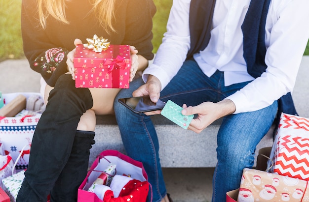 Foto gratuita pareja sentada con una pequeña caja de regalo en el banco