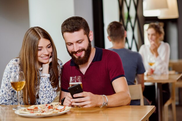 Pareja sentada en una pizzería con vino de pizza y cerveza