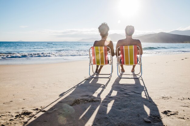 Pareja sentada en la playa formando sombras