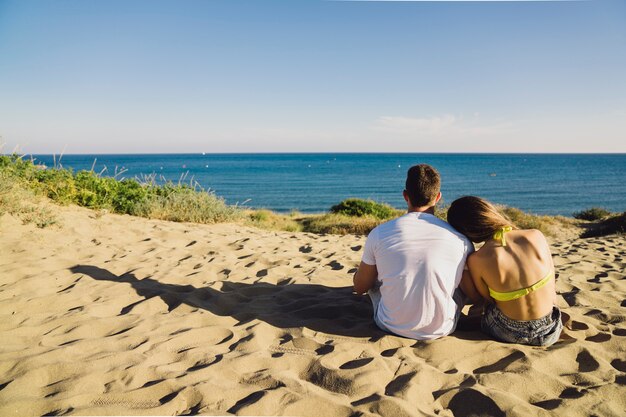 Foto gratuita pareja sentada en la playa