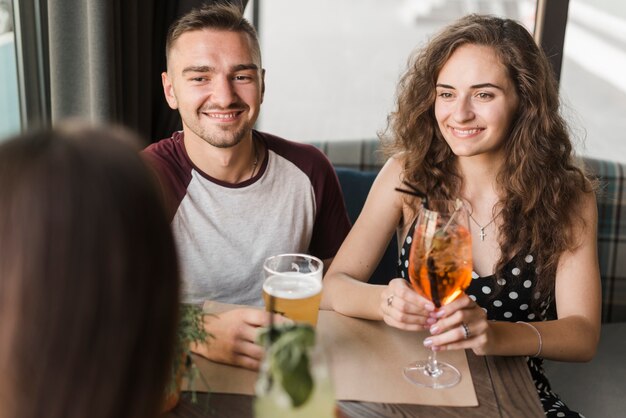 Pareja sentada en el restaurante disfrutando de bebidas con amigos