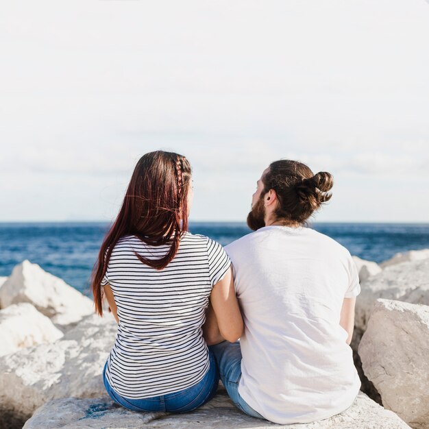 Pareja sentada en rocas por el mar