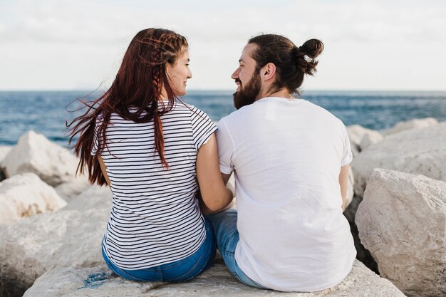 Pareja sentada en rocas por el mar