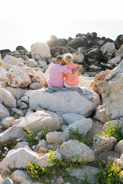 Pareja sentada en las rocas vista posterior