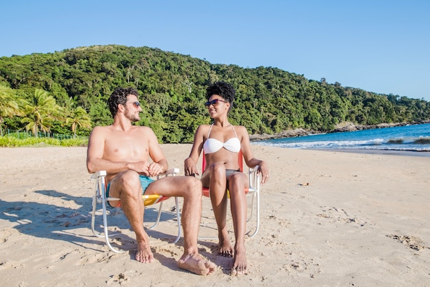 Pareja sentada en silla en la playa