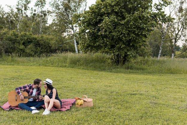 Foto gratuita pareja sentada sobre manta de picnic