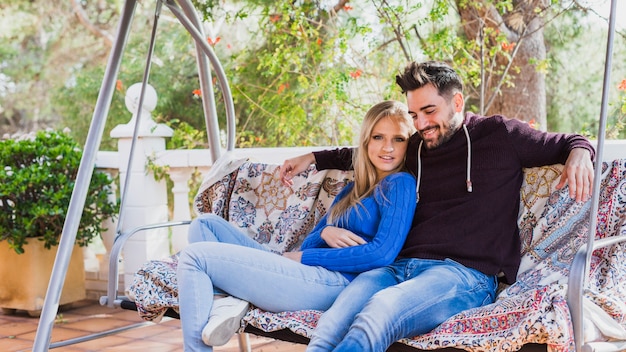 Pareja sentada en un sofá columpio en la terraza