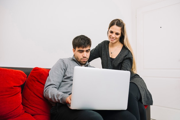 Pareja sentada en el sofá usando la computadora portátil