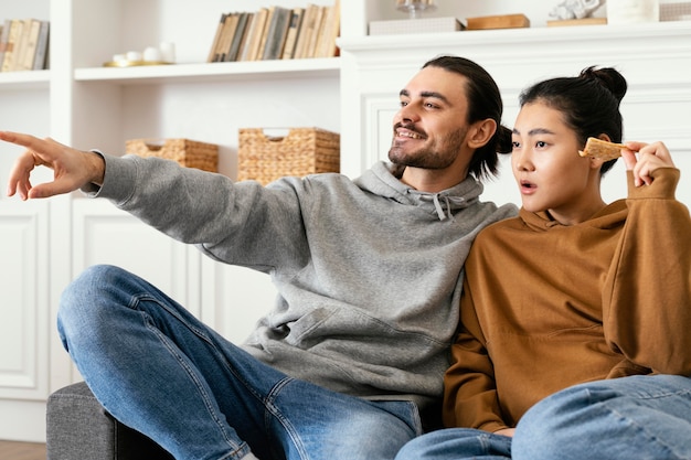 Foto gratuita pareja sentada en el sofá y viendo la televisión