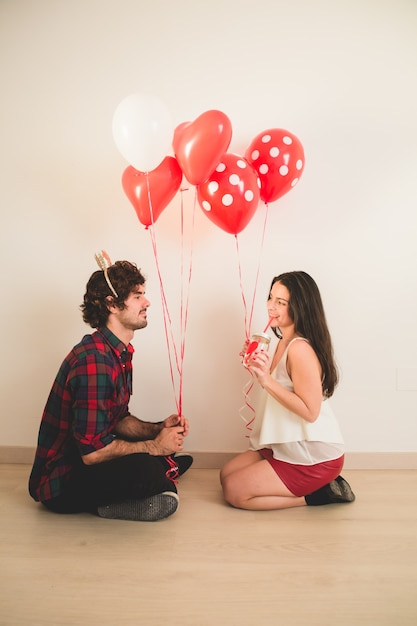 Pareja sentada en el suelo con globos en la mano