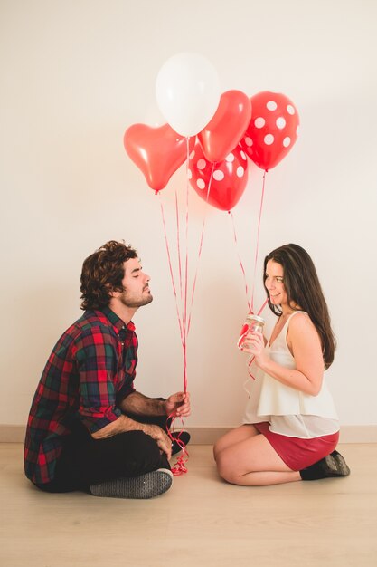 Pareja sentada en el suelo con globos en la mano