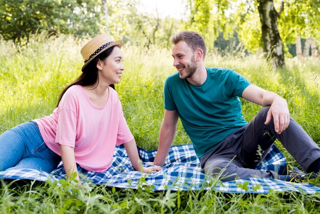 Pareja sentada en tela escocesa en picnic