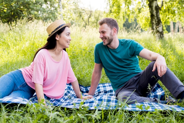 Pareja sentada en tela escocesa en picnic